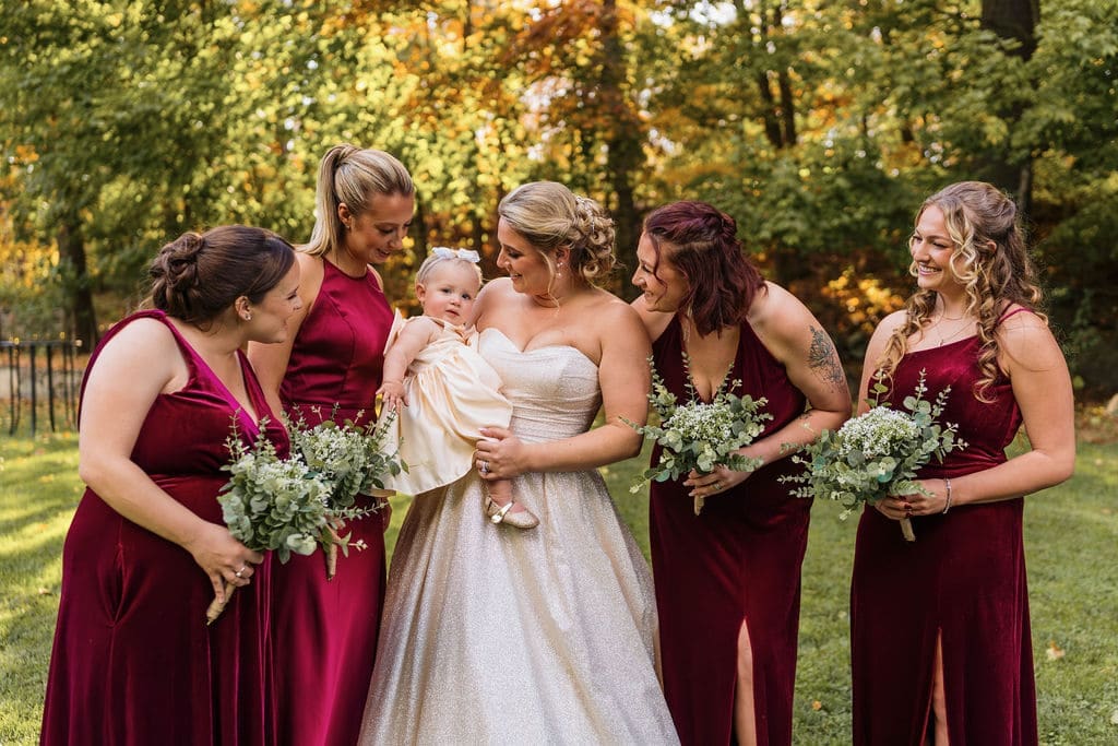 Bridal Party Posing For A Candid Photo with The Bride Holding a Baby