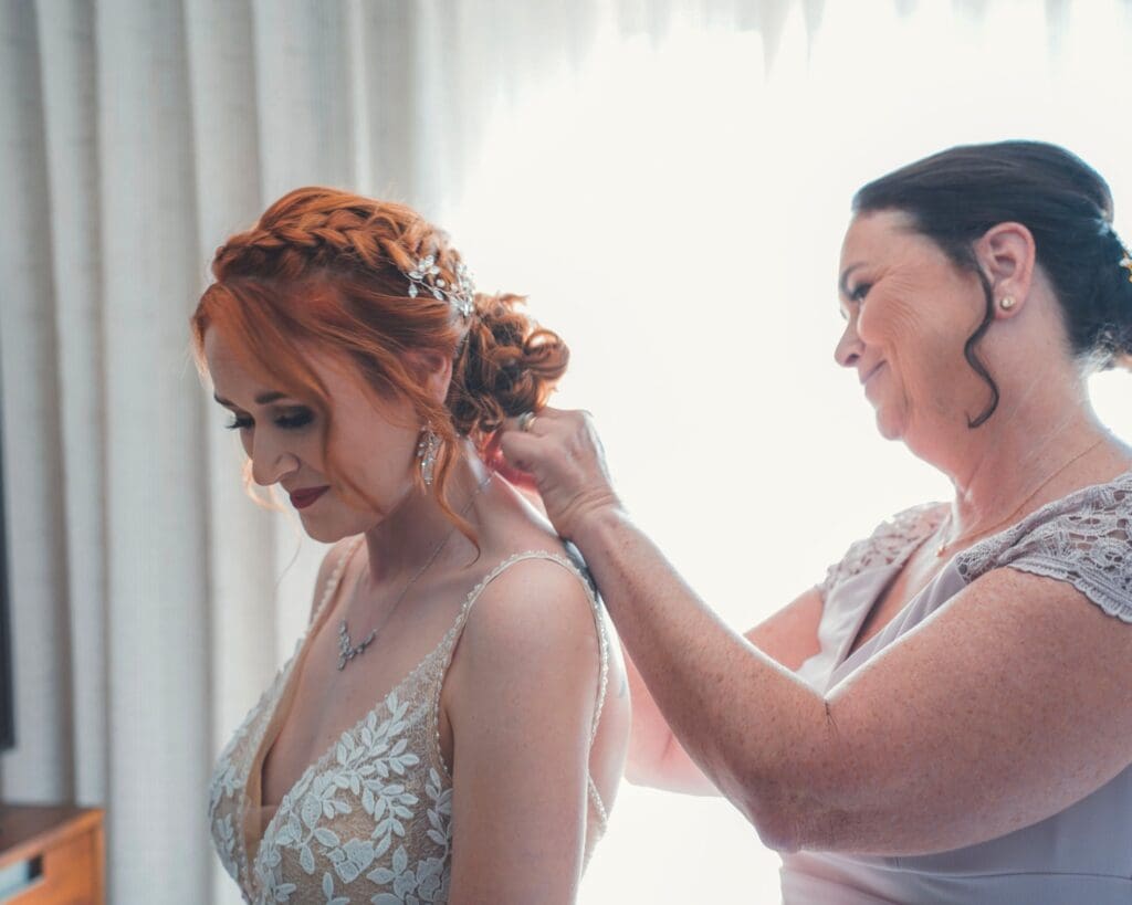 A Woman Putting A Necklace On The Bride