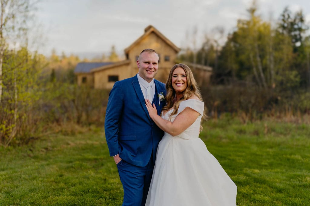 Groom and bride posing in front of the Barn at Bull Meadow