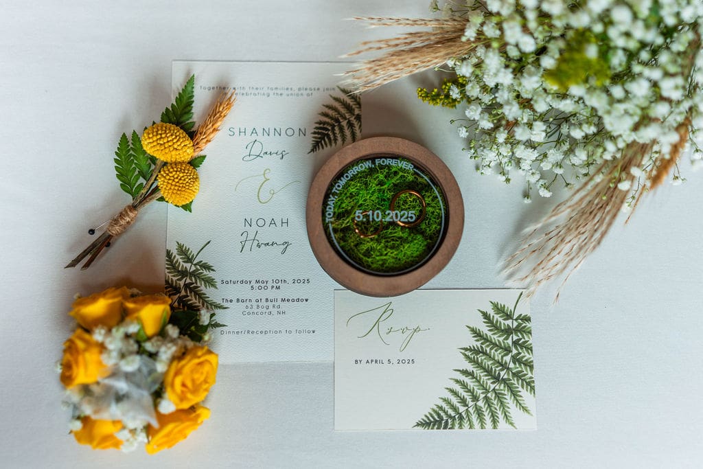 Wedding Invitation beside rings and flower